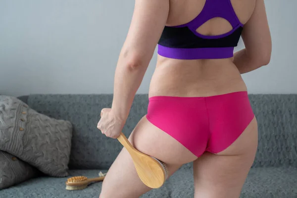 problem of orange peel skin, woman with cellulite is doing anti-cellulite massage on legs back part, buttocks with brush at home, get rid of fat, skin care, body perfection