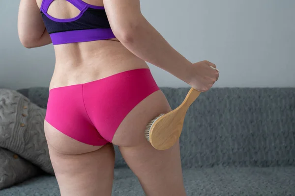 problem of orange peel skin, woman with cellulite is doing anti-cellulite massage on legs back part, buttocks with brush at home, get rid of fat, skin care, body perfection