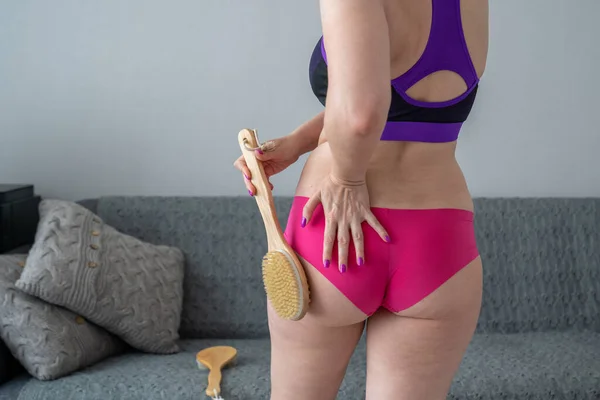 problem of orange peel skin, woman with cellulite is doing anti-cellulite massage on legs back part, buttocks with brush at home, get rid of fat, skin care, body perfection