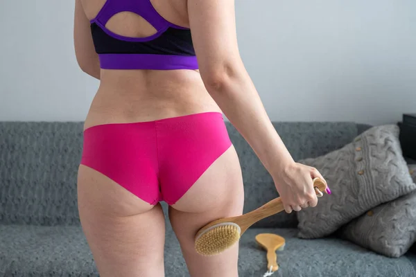 problem of orange peel skin, woman with cellulite is doing anti-cellulite massage on legs back part, buttocks with brush at home, get rid of fat, skin care, body perfection