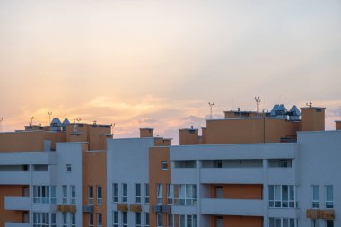 Şehrin üzerinde güzel turuncu günbatımı, binaların ve evlerin görünen şehir çizgisi, gökyüzünde karanlık ve güneş ışığı, sabahın erken saatlerinde, gün doğumunda 