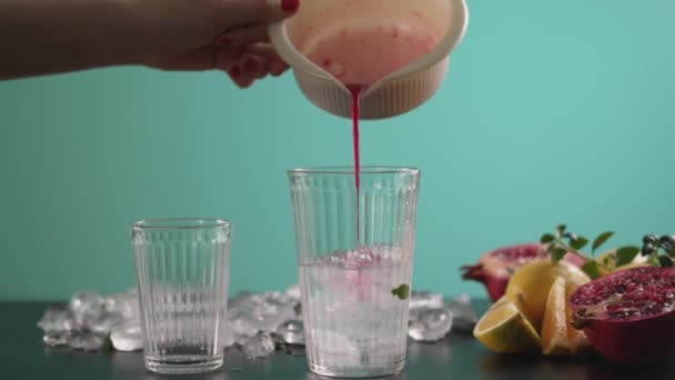 冷たい夏の明るいカクテルを準備します 氷のキューブと美しい透明ガラス 女性の手が赤い飲み物をグラスに注いで — ストック動画