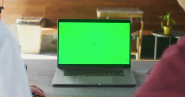 自宅に座っている間 クロマキーとノートパソコン上でオンラインでカップルのビデオチャットの閉鎖 男性と女性の肩のビューの上にビデオ通話で緑の画面コンピュータ上で話す — ストック動画