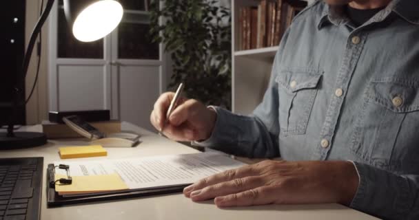 Äldre Man Skriver Natten Ett Rum Vid Ett Bord Skrivbordslampa — Stockvideo