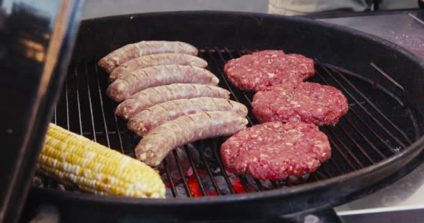 Würstchen Und Schnitzel Mit Mais Auf Einem Dampfenden Grill Über — Stockvideo