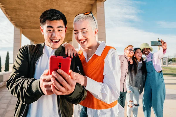 Par eller vänner tittar på och har kul med en smart telefon — Stockfoto