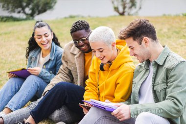 Bir grup öğrenci dışarıda çimlerin üzerinde oturuyor. Yüksek Kalite Fotoğraf
