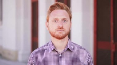 Ciddi kızıl saçlı adam dışarıda kameraya bakıyor. Üzgün bir gencin yakın portresi. Yüksek kalite 4k görüntü