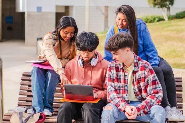 Bankta oturan genç konsantre öğrencilerin görüntüsü. Bilgisayarı kullanırken yana bakıyor... yüksek kalite fotoğraf