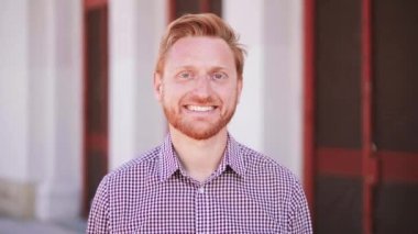 Açık havada kameraya gülümseyen mutlu kızıl saçlı adamın yakın portresi. Yüksek kalite 4k görüntü