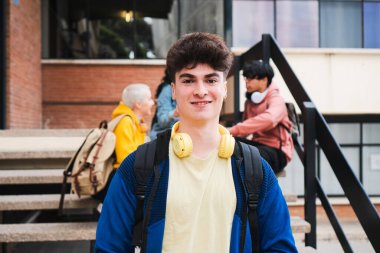 Bir üniversite öğrencisinin portresi sırt çantası taşıyor ve merdivenlerde dikiliyor.