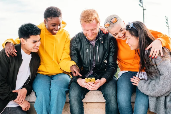 Five young friends watching a video in a mobile phone and smiling together. high quality photo