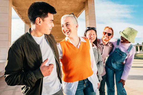 Couple of friends talking and smiling. In the back three friends smiling and having fun outdoor. high quality photo