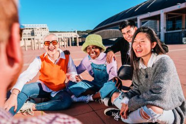 Group of diverse friends laughing and talking sitting on the floor outdoors. high quality photo