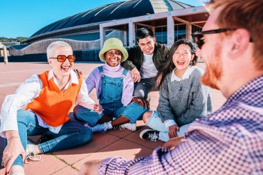 young group of friends laughing sitting together on the floor outdoor. high quality photo