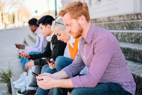 Friends using smartphones and browsing on internet sitting outdoors. high quality photo