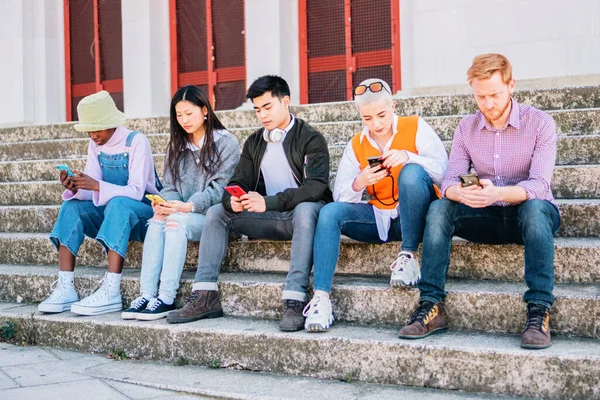 group of friends browsing with their mobile phones sitting outdoors. high quality photo