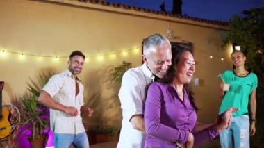 Multiethnic couple doing romantic dance and showing their love at background his friends dancing and celebrating the night. High quality 4k slowmotion footage