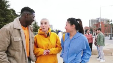 Group Of Three Multiethnic Teenage Students Standing Outside College Building tlking bout homeworks, at the background five friends laughing. High quality 4k footage