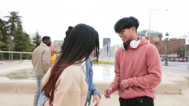 Group Of Three Multiethnic Teenage Students Standing Outside College Building tlking bout homeworks, at the background five friends laughing. High quality 4k footage