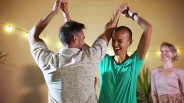 mature man and happy woman dancing latin music and having fun, his friends at the background enjoying the night party. High quality 4k slowmotion footage