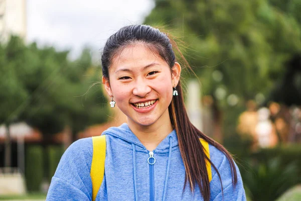 Young chinese lady student smiling looking at camera at the high school. Close up portrait of cute asian girl standing and laughing at campus. High quality 4k footage