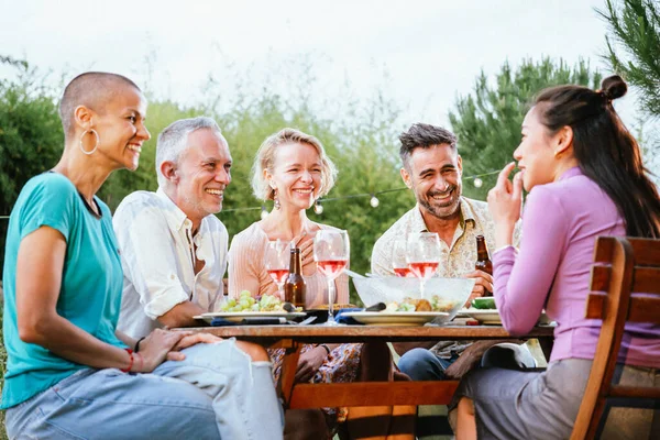 Bir grup yetişkin arkadaş mı, yoksa arka bahçedeki bir akşam yemeği partisinde oturup eğlenmek mi? Yaşam tarzı konsepti. Yüksek kalite fotoğraf