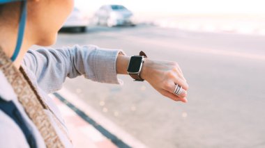 Close up hand woman people wear smart watch checking time and health information at outdoor on day. Modern lifestyle with technology gadget concept.