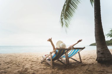 Yaz tatili, Tayland, Pattaya 'da plaj sandalyesinde elini kaldıran genç Asyalı kadın.