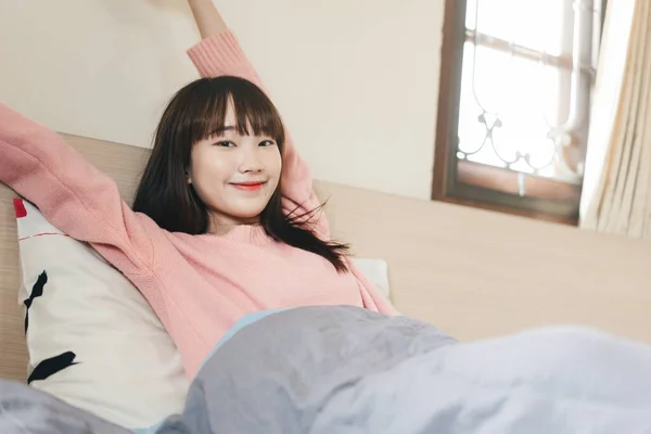 寝室で幸せなアジアのティーンエイジャーの女性 目を覚ますと 朝のピンクのセーターを着て腕のストレッチ ホームコンセプトでのライフスタイルステイ — ストック写真