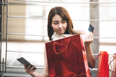 Güzel genç Asyalı kadın akıllı telefon alımı yapıyor ve kredi kartıyla çevrimiçi nakit ödeme yapıyor. Bayram indirimi konsepti alışverişi. Şehir kızı yaşam tarzı mutlu açık hava aktiviteleri.