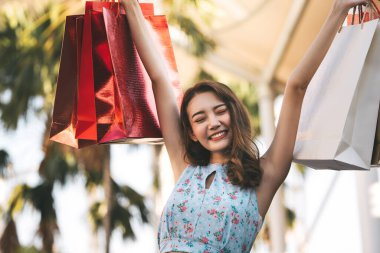 Tatillerde bekâr olmak. Alışveriş torbalarıyla büyüyen mutlu, genç Asyalı kadın. Kopyalama alanı olan arkaplan.