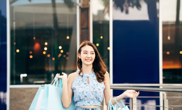 幸せな笑顔の顔若い大人のアジアの女性でショッピングバッグ 日の屋内デパートで — ストック写真