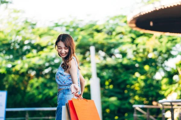 幸せな若い大人のアジアの女性を保持ショッピングバッグ日 店頭販売の季節のコンセプトでお楽しみください — ストック写真