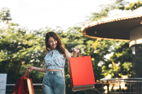 Tatillerde bekâr olmak. Genç, mutlu Asyalı kadın alışveriş torbalarını tutuyor. Kopyalama alanı olan arkaplan.