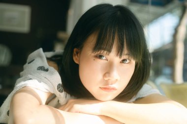 Kameraya bakan genç Asyalı kadın portresi. Minimal moda. Gün içinde kapalı arkaplan.