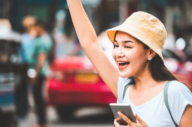 Sırt çantalı, beyaz gömlekli, mutlu Asyalı genç bir kadın. Akıllı telefonu tut. Turizm için bir taksi çağırın. Khaosan yol geçmişi. Bangkok Şehri, Tayland
