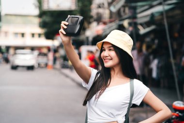 Sırt çantalı mutlu genç Asyalı gezgin kadın. Fotoğraf makineli bir selfie. Khaosan sokak pazarını gezmek. Bangkok Şehri, Tayland