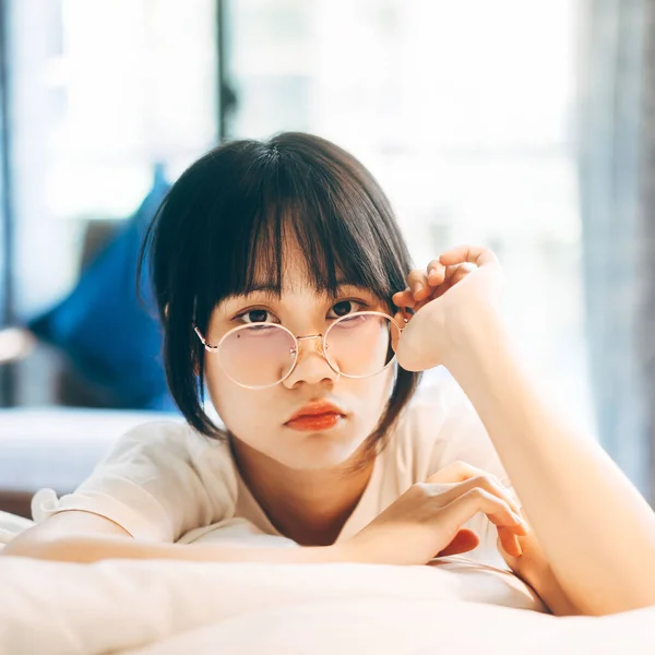 肖像画の若い大人のアジアの女性 女性は目の魅力的な外観のカメラで家に滞在目を覚ます後 寝室でリラックスします 眼鏡と白いシャツを着用 — ストック写真
