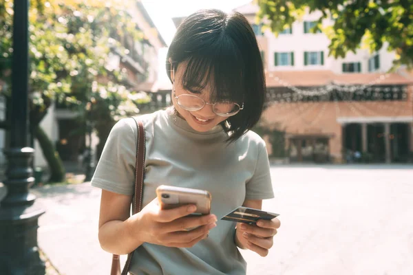 商界人士通过在线应用媒体购物的概念 年轻的亚洲成年女性消费者使用Creadit卡和智能手机 城市白天背景 有复制空间 — 图库照片