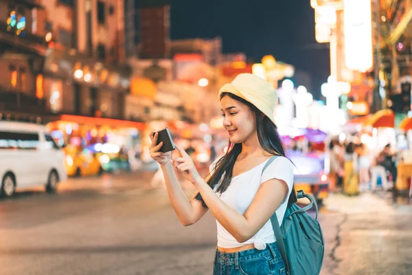 Sırt çantalı, beyaz gömlekli, mutlu Asyalı genç bir kadın. Yaowarat 'ın yanında fotoğraf makinesi ile fotoğraf çekmek. Çin Mahallesi sokak yemekleri. Bangkok Şehri, Tayland