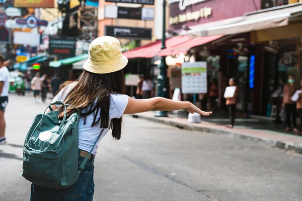 Genç Asyalı gezgin, beyaz gömlekli, sırt çantalı, mutlu bir kadın. Turizm için bir taksi çağırın. Khaosan yol geçmişi. Bangkok Şehri, Tayland