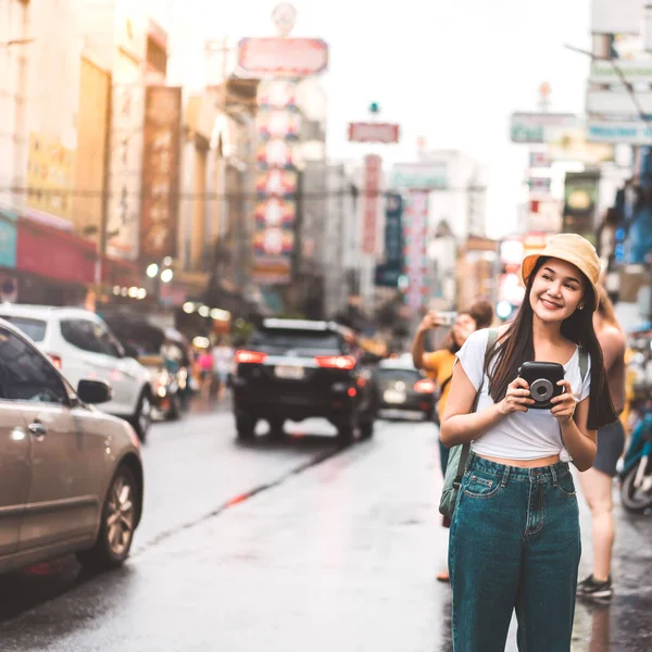 Genç Asyalı yalnız gezgin kadın rahat bir şekilde sırt çantasıyla rahatla. Yaowarat 'ta yürürken anlık kamerayla fotoğraf çek. Çin kenti sokak yemekleri arka planda. Bangkok Şehri, Tayland