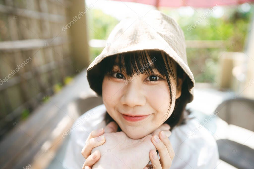 POV view portrait of lovely girlfriend. Happy young adult asian woman looking camera. Face on couple hand at outdoor on day. Wearing bucket hat and white shirt.