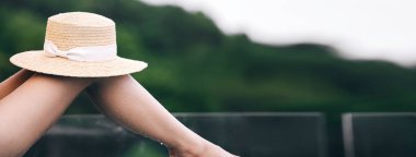 Lüks seyahat, rahatlama ve kaplıca konsepti. Asyalı kadının şapkası ıslak bacağı, açık havada havuz başında. Kopyalama alanı olan bulanık arkaplan.