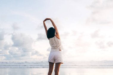 Yetişkin Asyalı genç bir kadının elini uzatması ve kumsalda güneş ışığı ve açık gökyüzü ile dinlenmesi. Phuket, Tayland 'da yurt içi seyahat.