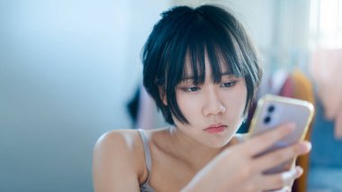 Modern teknoloji konsepti olan bir yaşam tarzı. Sabahları teletıp ve akıl sağlığı konsepti için elinde akıllı telefon tutan mutlu, genç, yalnız bir kadın..