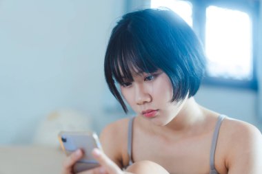 Modern teknoloji konsepti olan bir yaşam tarzı. Sabahları teletıp ve akıl sağlığı konsepti için elinde akıllı telefon tutan mutlu, genç, yalnız bir kadın..