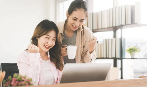 İlişki konseptiyle birlikte yaşayan iki yetişkin kadın. Ev ofisinde ya da apartmanda gülen Asyalı mutlu bir çift. İnternetten alışveriş yapmak ve çalışmak için dizüstü bilgisayar kullanmak.