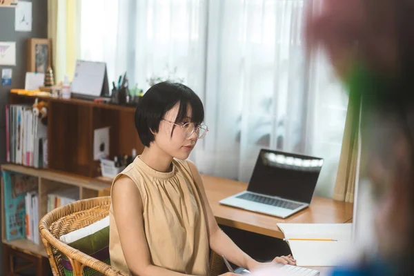 Young adult asian woman stay and work from home office concept. Female using computer for career via internet online. Background with computer indoor on day.